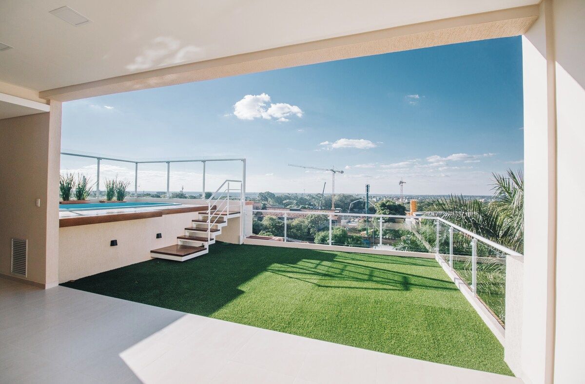 Interior moderno com varanda com vista para uma piscina e céu azul.