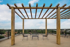 Eine Pergola aus Holz auf einer Dachterrasse mit Blick auf die Stadtlandschaft.