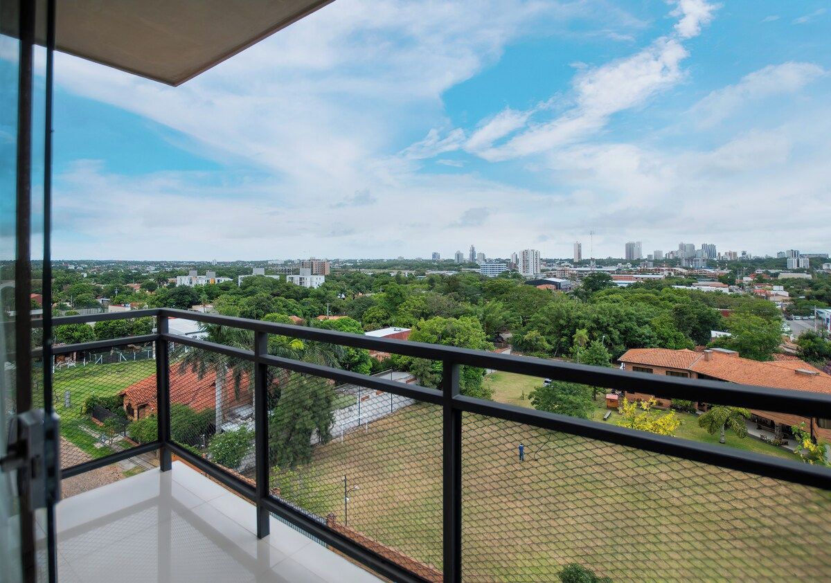 Un balcon offrant une vue sur le paysage urbain, avec ses bâtiments et sa végétation.