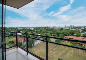 Un balcon offrant une vue sur le paysage urbain, avec ses bâtiments et sa végétation.