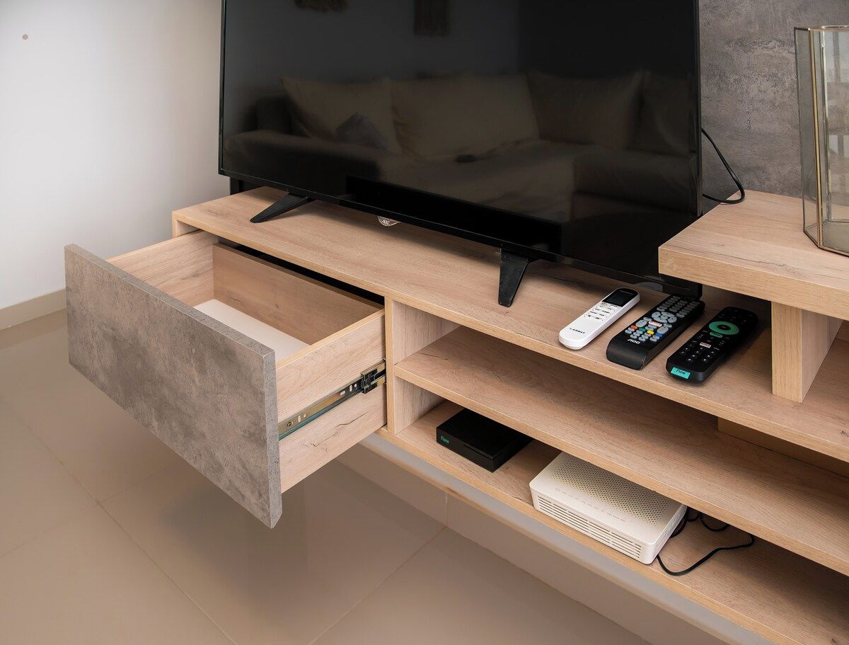 A modern entertainment unit with a flat-screen TV, remote controls, and a drawer.