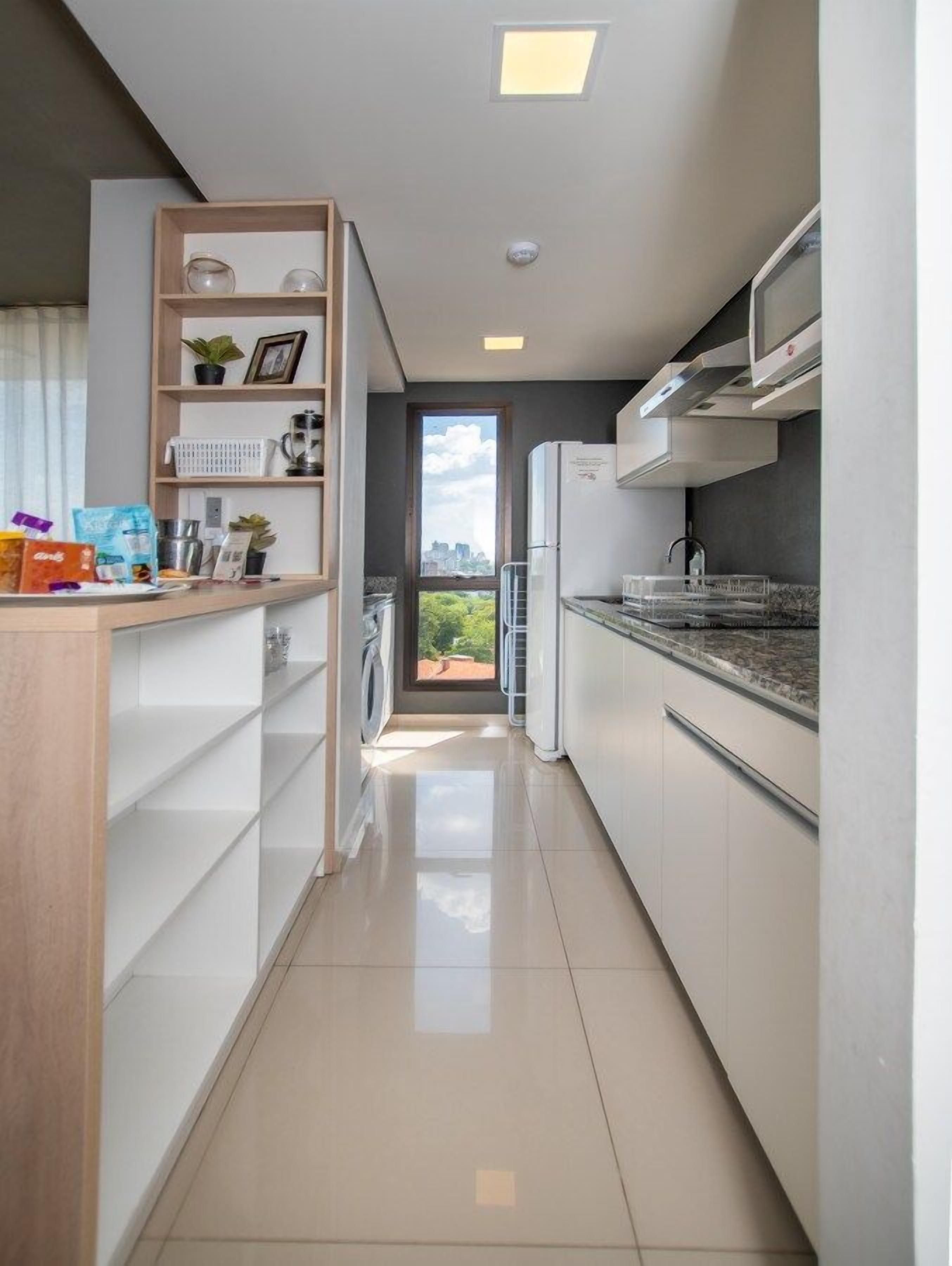 A modern kitchen with a built-in oven, a microwave, and a sink. There is a window providing a view of the outdoors.