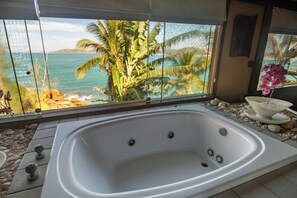 A spa area with a large bathtub, a view of the ocean, and tropical plants. - Cinematic mansion Geriba and Ferradurinha (Armação dos Búzios)