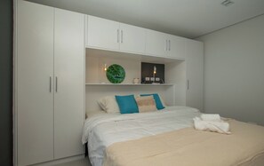 A bedroom with a bed, white wardrobe, and a shelf with decorative items. - Business Stay with Fast Wi-Fi, Pool and Workspace (Asunción)