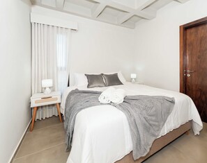 Un dormitori amb llit, una nit, una làmpada i una porta.