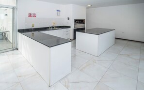 A modern kitchen with white cabinetry, a black countertop, and a built-in oven. - Modern Retreat with Pool, Gym and Private Balcony (Asunción)