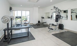 A gym with a bench press, weight rack, and various exercise machines. - Modern Retreat with Pool, Gym and Private Balcony (Asunción)