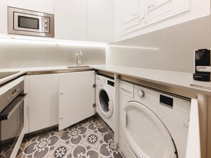 Una cocina compacta equipada con microondas, lavavajillas, lavadora y fregadero.