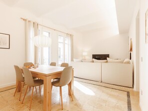A modern living room with a dining area, featuring a wooden table and chairs, a sofa set, and a television. - Bravissimo Santa Clara 53, Central 3-bedroom near Plaça Independència (Girona)