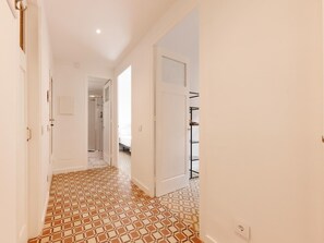 A hallway with patterned flooring, white walls, and a door leading to a bathroom. - Bravissimo Santa Clara 53, Central 3-bedroom near Plaça Independència (Girona)