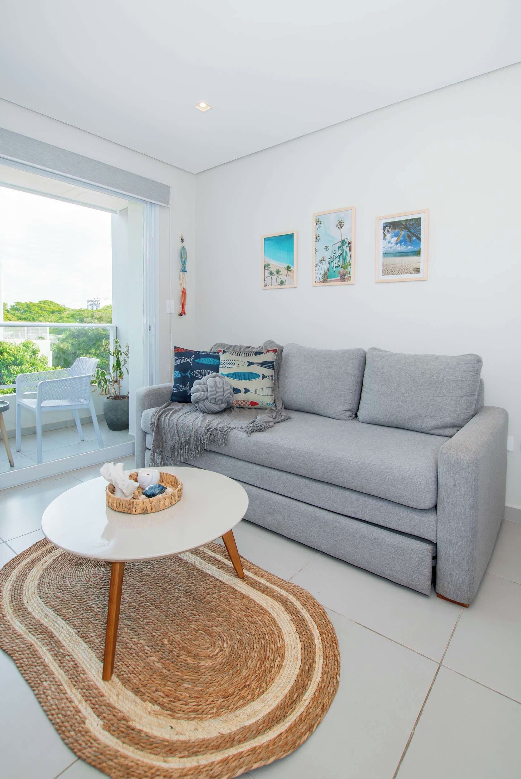 Una sala de estar moderna con un sofá gris, una mesa de centro redonda y vistas al exterior con vegetación.