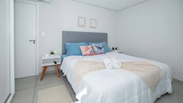 Un dormitorio moderno con cama, mesitas de noche y aire acondicionado de pared.