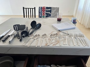 A table with various kitchen utensils and a notebook. - Serene 2-bedroom house in Conkal perfect for relaxing getaways (Conkal)