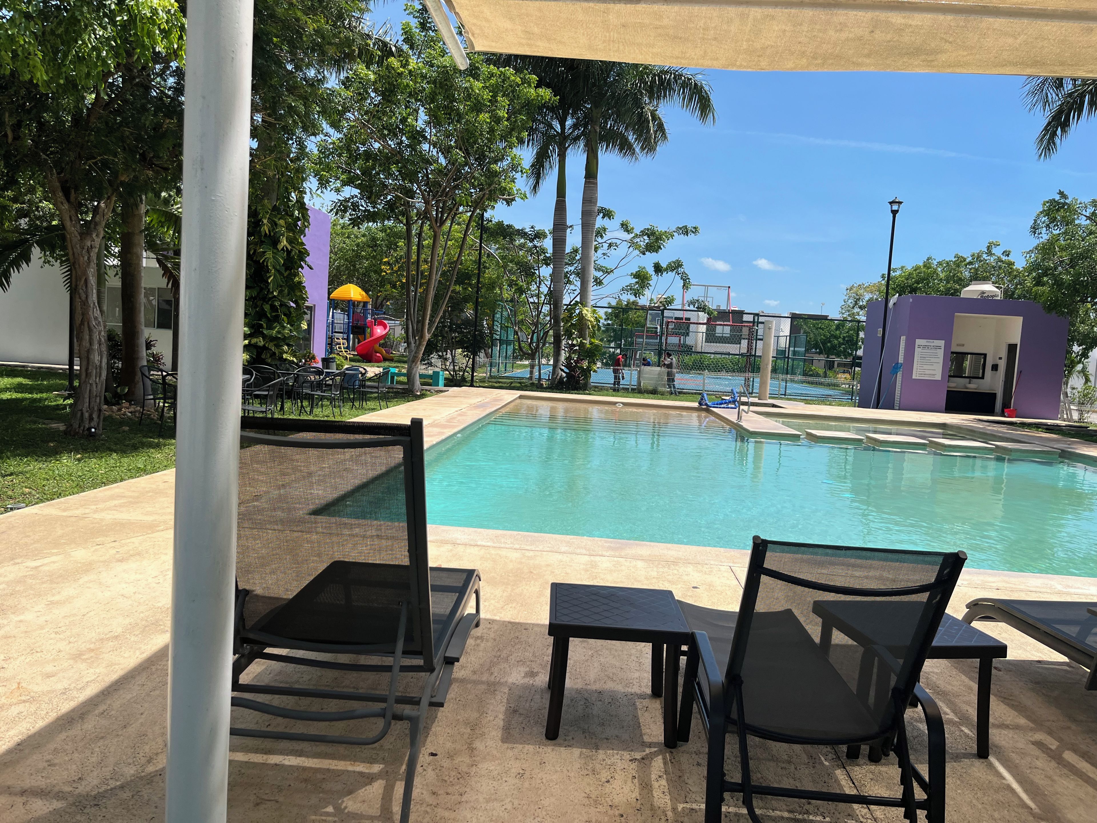 A pool area with lounge chairs and a children's play structure.