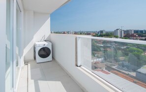 Un balcon avec un lave-linge, une vue dégagée sur le paysage urbain et un sol carrelé.