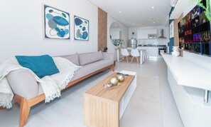 Un salon moderne avec un canapé, une table basse et des œuvres d’art accrochées au mur.