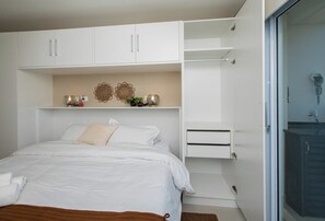 A bedroom with a bed, white wardrobe, and a bathroom with a shower. - Stunning Hub with City Views, Pool and Balcony (Asunción)
