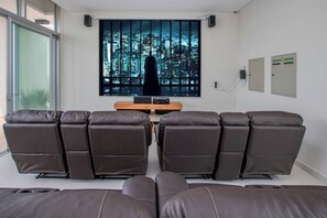 Ein Zimmer mit großem Fenster, einem Flachbildfernseher und mehreren Liegesesseln.