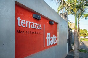A red sign with the words 'terrazas flats' and 'Monico Candia 435' on a building facade. - Peaceful One BR Apt with Great Living Space & WiFi (Asunción)