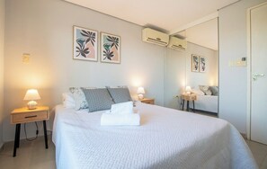 Ein Hotelzimmer mit einem Bett, zwei Nachttischen, einem Spiegel und Wandbildern.