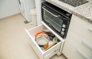 A kitchen with a built-in toaster oven and a drawer containing a colander and a pot. - Peaceful One BR Apt with Great Living Space & WiFi (Asunción)