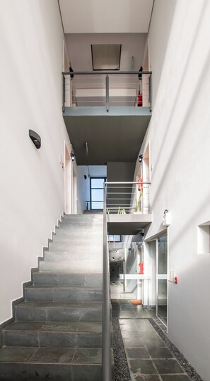 A staircase leading to a second floor with a metal railing, a fire extinguisher, and a glass door. - Peaceful One BR Apt with Great Living Space & WiFi (Asunción)