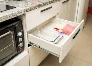 A kitchen with a microwave, a drawer with a clear glass baking dish, and a red cloth. - Peaceful One BR Apt with Great Living Space & WiFi (Asunción)
