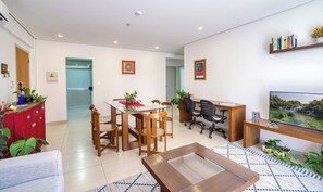 A modern living room with a dining area, a TV, and a bookshelf. - Executive Stay, Pool & Parking, Near US Embassy (Asunción)