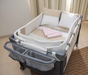 A baby crib with a mesh footrest and a pink towel. - Executive Stay, Pool & Parking, Near US Embassy (Asunción)