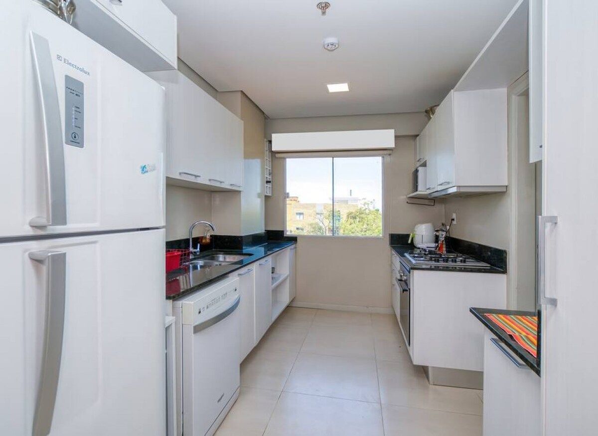 Cuina moderna amb armaris blancs, rentaplats integrat i finestra amb vista exterior.