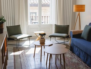 Ein modernes Wohnzimmer mit zwei Sesseln, einer Couch, einem kleinen Tisch und einer Stehlampe.