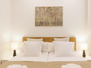 A hotel room with a large bed, two bedside lamps, and a wall-mounted abstract painting. - Bravissimo Ciutadans C, with 2 bedrooms (Girona)