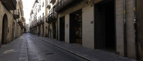A narrow street with buildings on either side, some with visible storefronts and signage.