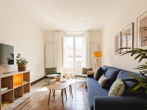A modern living room with a sofa, a TV, a coffee table, and a floor lamp. - Bravissimo Ciutadans C, with 2 bedrooms (Girona)