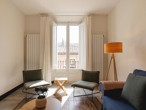 A room with two chairs, a sofa, a table, a floor lamp, and a view through a door. - Bravissimo Ciutadans C, with 2 bedrooms (Girona)