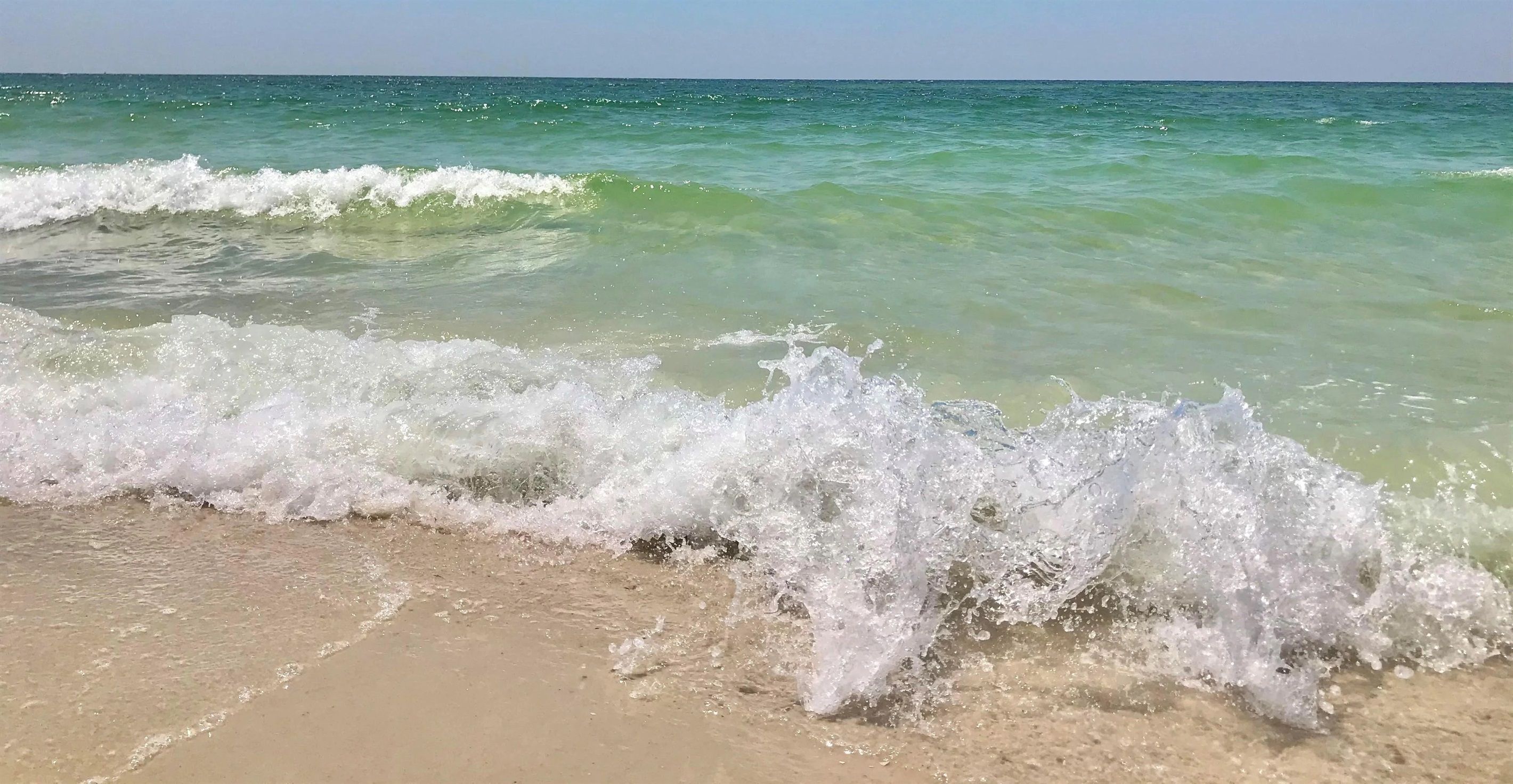 A beach with waves crashing onto the shore.