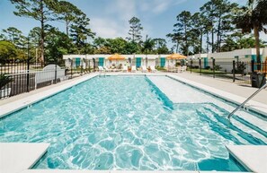 Una piscina rectangular con agua azul cristalina, rodeada por una terraza blanca y una valla de metal negro.