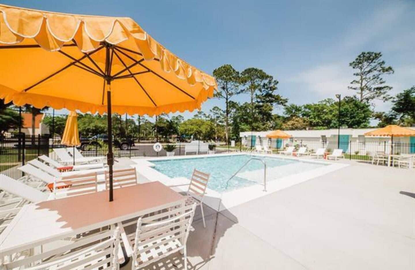 Ein Poolbereich mit Liegestühlen und Sonnenschirm.