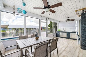 Eine Außenpatio mit Esstisch und Stühlen, einem Pool und einer Küchenzeile mit Steinrückwand.