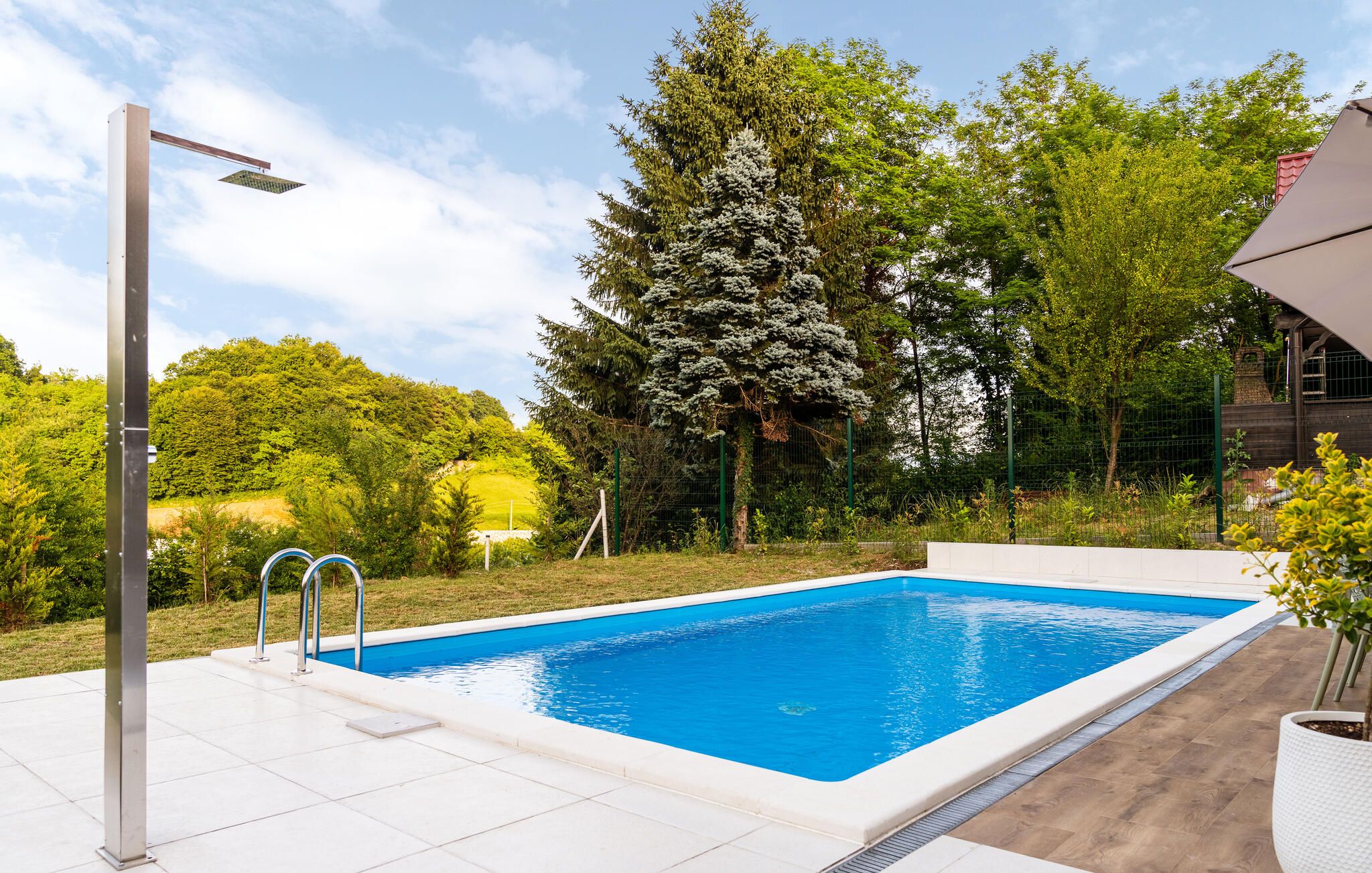 Une piscine rectangulaire à l’eau d’un bleu limpide, entourée d’une terrasse carrelée de blanc.