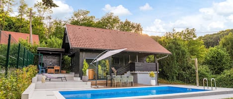 A modern house with a swimming pool, outdoor seating, and a covered patio.