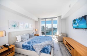 Een moderne hotelkamer met een groot bed, een televisie, een bureau en uitzicht op de stad.