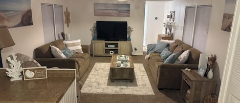 Un salon comprenant deux canapés, une table basse, un téléviseur et des objets de décoration.