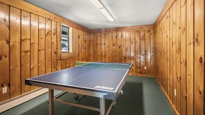 Ein Tischtennistisch in einem Raum mit Holzwänden und einem grünen Teppich.