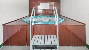 Wellnessbereich mit Holzbänken, Whirlpool und einer Beschilderung mit Anweisungen.