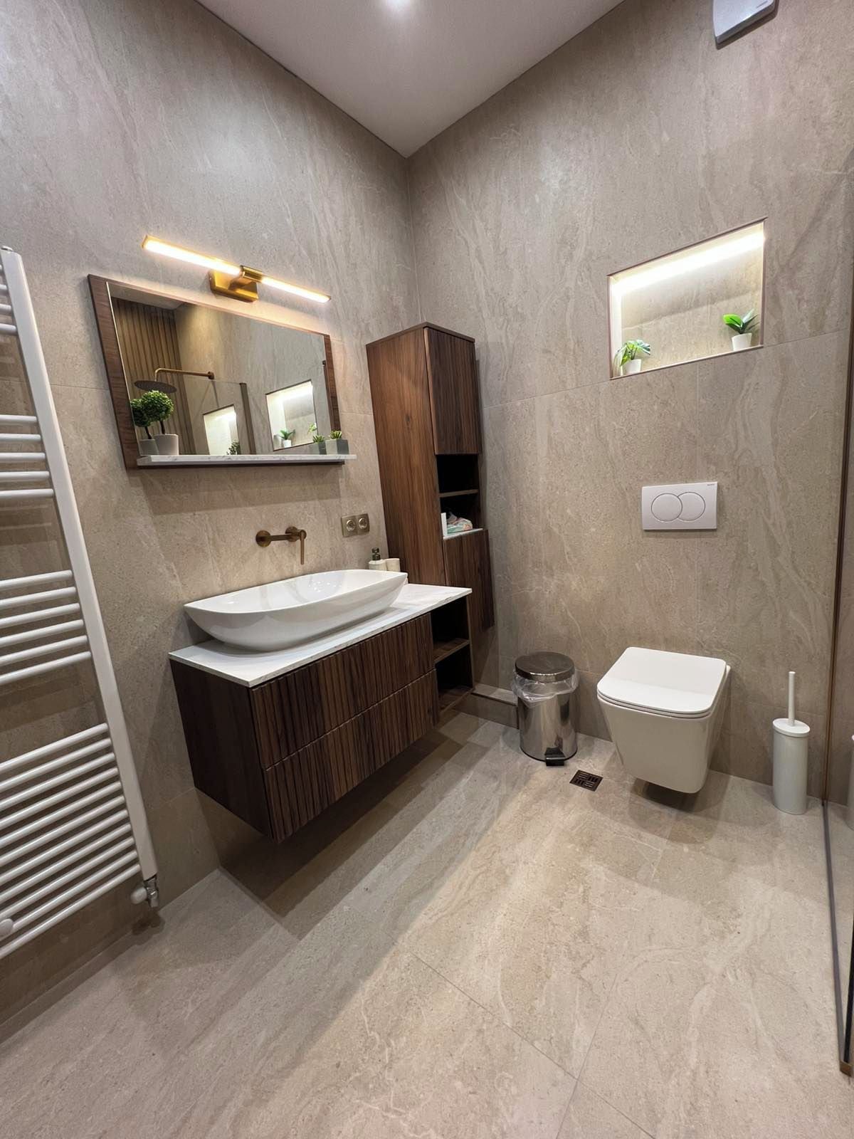 Un baño moderno con un lavamanos grande, un inodoro, un espejo y un perchero para toallas.