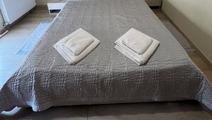 Un dormitori amb un llit, una taula de nit, un radiador i una petita taula al costat del llit.