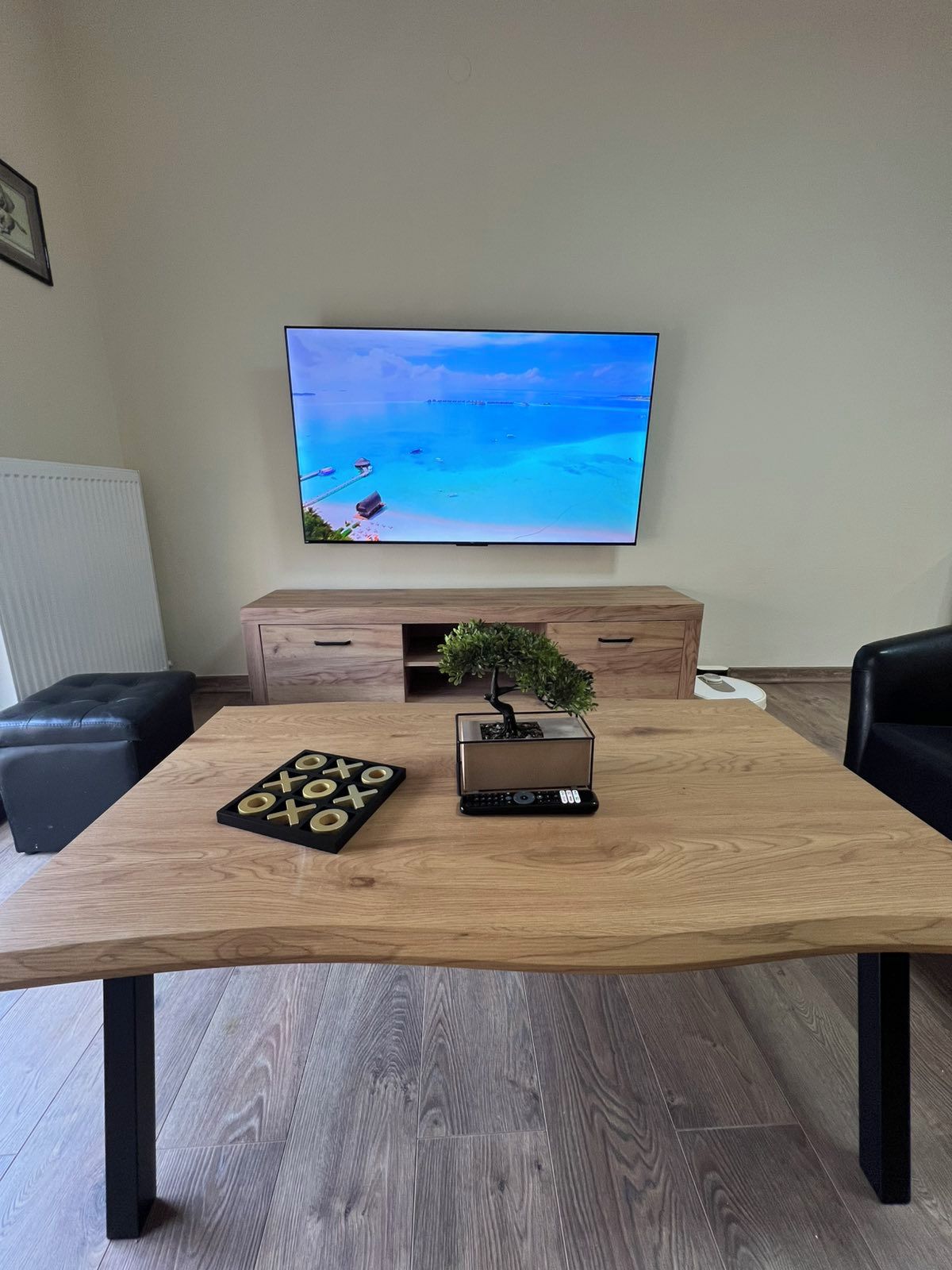 A room with a wooden table, a television on the wall, a small plant, and a board game.