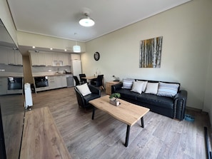 Un apartamento moderno con comedor, un sofá de cuero negro y una mesa de centro de madera.