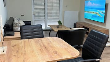 Un salón de conferencias con una mesa de madera, sillas negras, un sofá y un televisor que muestra una vista panorámica.